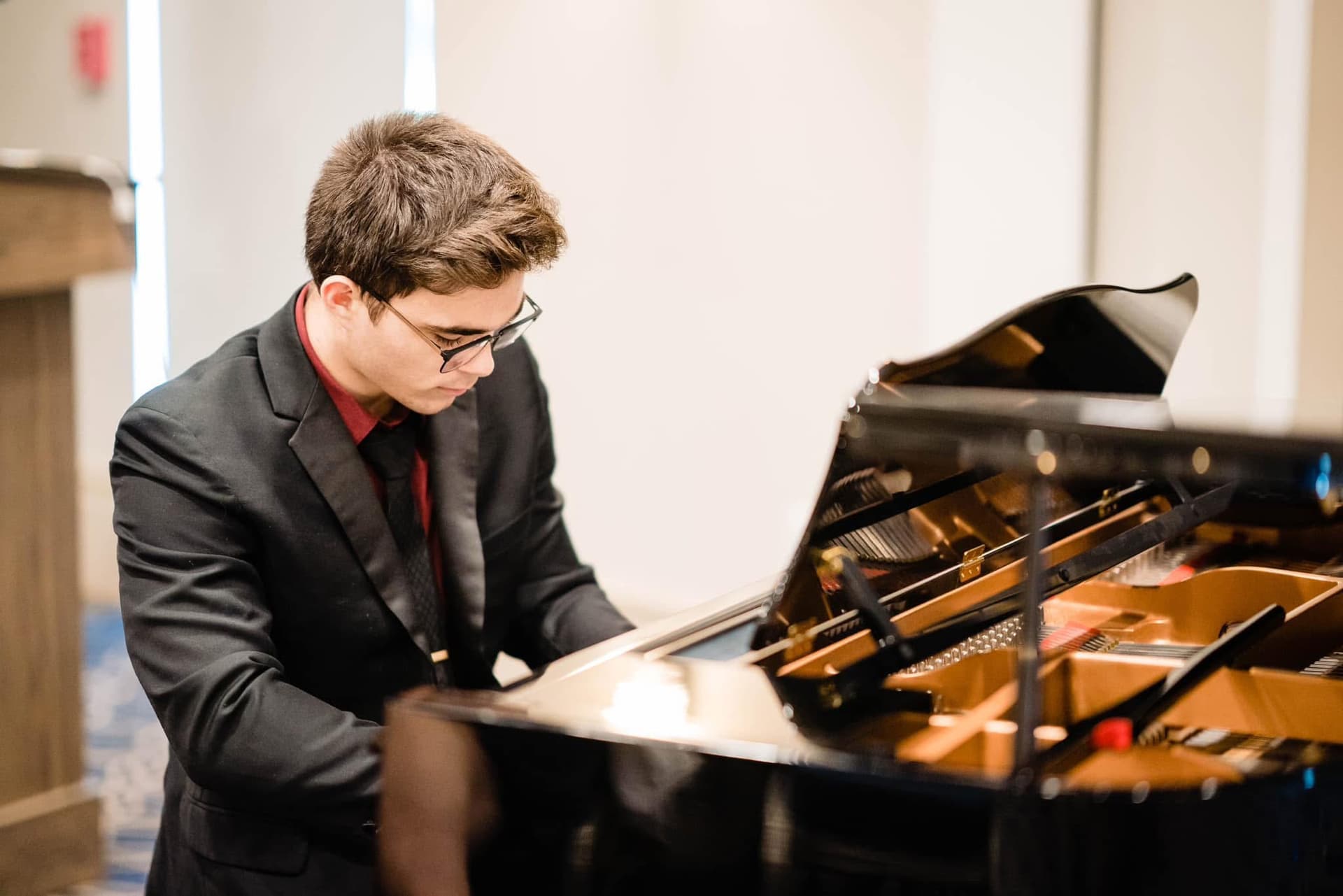 Student performing at a grand piano during a recital